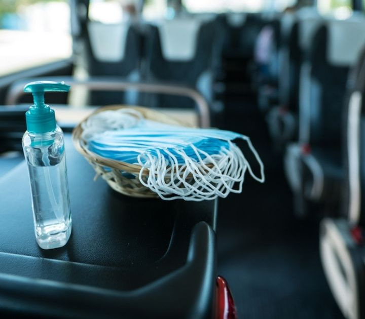 Hand sanitizer and medical face mask on a charter bus