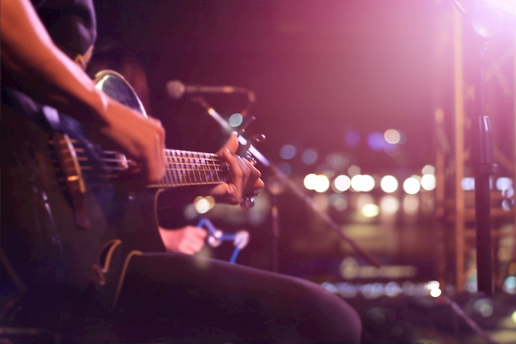 a man plays his guitar on the stage of an Austin live music venue