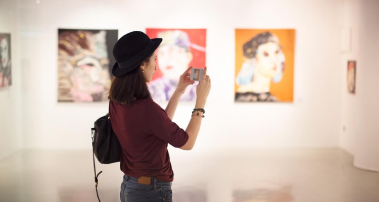 A woman taking a photo at a fine arts museum.