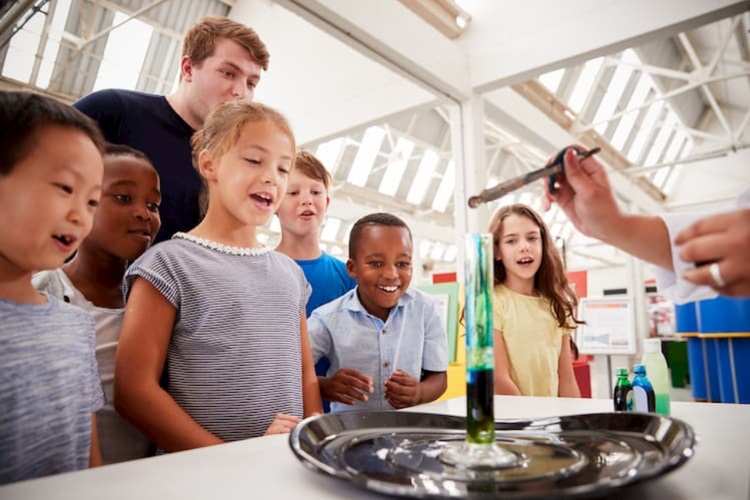 A group of children watching a science experiment at a museum.