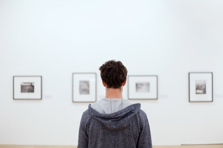 A man looking at pictures on a wall.